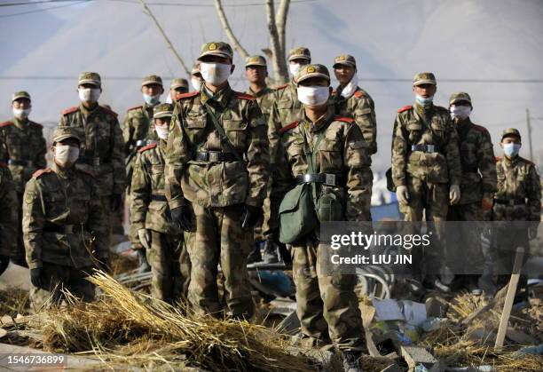 Chinese rescue soldiers stand on rubbles as listen to a briefing amid earthquake devastation in Jiegu, Yushu County, on April 17, 2010. China began...