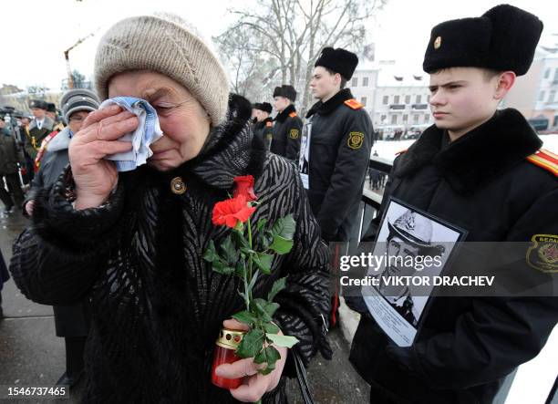 Woman wipes a tear as she passes by cadets in Minsk on February 15 who hold portraits of Soviet soldiers killed in Afghanistan during the 1979-1989's...