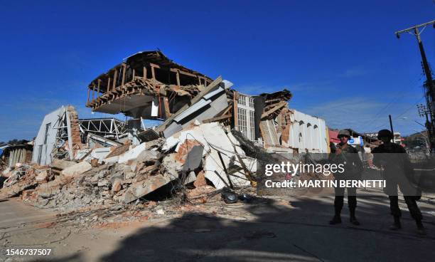 Soldiers stand guard by a wrecked building on March 2, 2010 in the fishing village of Constitucion, central Chile, where more than 300 bodies have...