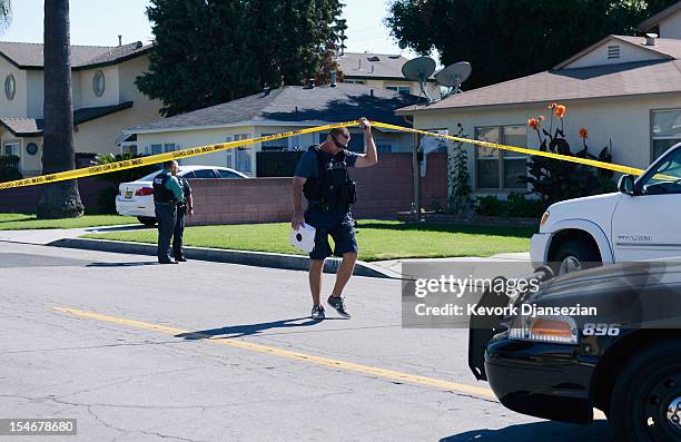 Police stand outside two story house after a shooting and at a fire protection business nearby killing two people and injuring three others on...