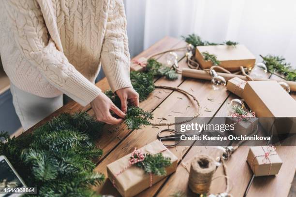 woman holding stylish modern christmas wreath with velvet ribbon and golden bells on white wall background. holiday decor, moody image. merry christmas and happy holidays - wreath making stock pictures, royalty-free photos & images