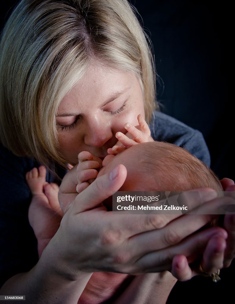 Mother kissing her newborn baby boy