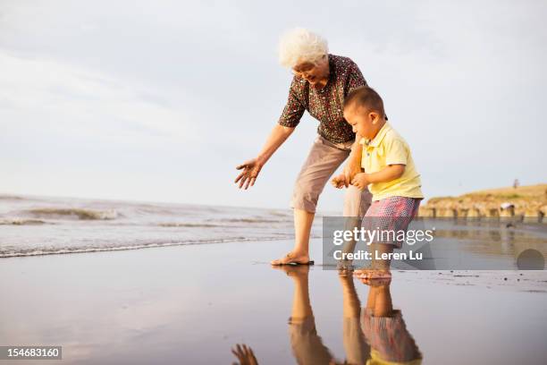 grandmother and little boy are playing on beach - asian granny pics stock-fotos und bilder