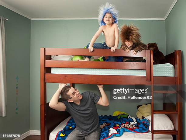 father looking at kids who are wearing rocker wigs - bunk beds for 3 stock-fotos und bilder