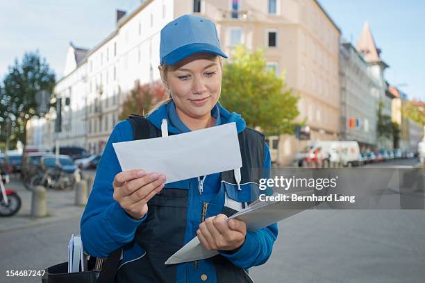 female postal worker looking through mail - postbode stockfoto's en -beelden