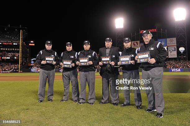 The Umpiring crew is seen on the field holding up Stand Up 2 Cancer signs during the fifth inning of Game 1 of the 2012 World Series between the...