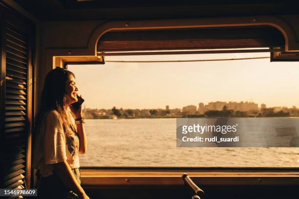 portrait of happy woman who travels on a boat during sunset on nile river, cairo - commuter ferry stock pictures, royalty-free photos & images