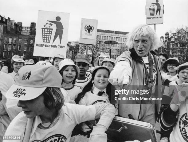 English dj and television presenter Jimmy Savile with a group of children during a 'Keep Britain Tidy' campaign event, 6th March 1979.