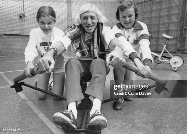 English dj and television presenter Jimmy Savile , with pupils at the William Gladstone High School in Brent, London, 20th October 1977. Savile is at...