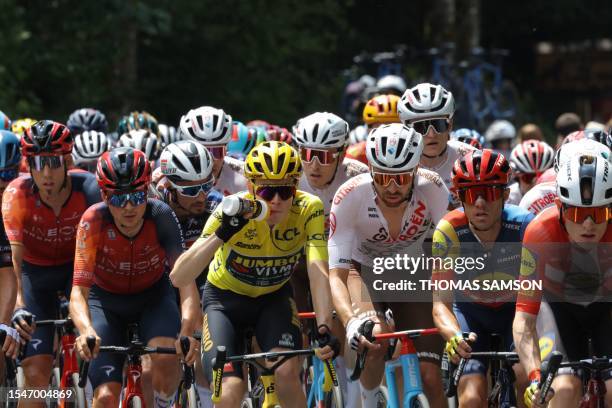 Jumbo-Visma's Danish rider Jonas Vingegaard wearing the overall leader's yellow jersey drinks as he cycles with the pack of riders during the 20th...