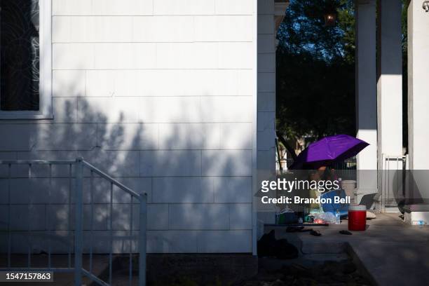 Person adjusts the umbrella while sitting in the shade during a heat wave on July 15, 2023 in Phoenix, Arizona. Weather forecasts today are expecting...
