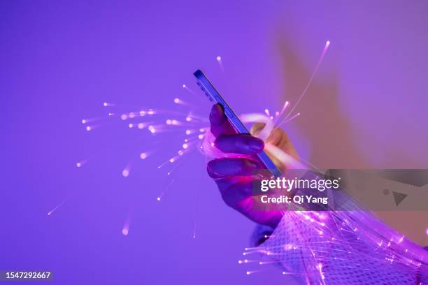 close-up of holding smartphone and fiber optic - software solutions photos et images de collection