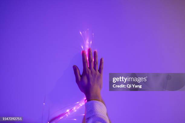 close-up of a hand touching an optical fiber - purple computer code stock pictures, royalty-free photos & images
