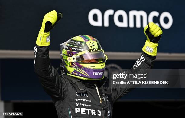 Mercedes' British driver Lewis Hamilton stands on his car as he celebrates winning the pole position after the qualifying session at the Hungaroring...
