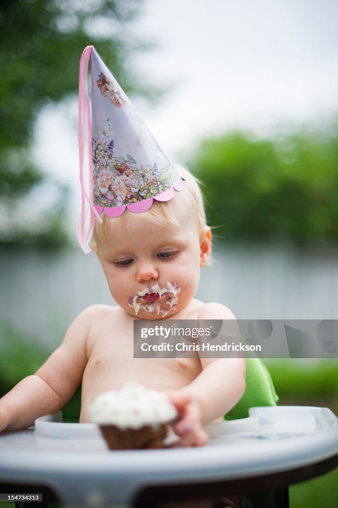 Baby girl eating cake on her first birthday