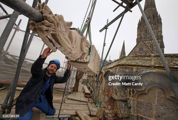 Stonemason Matt Barton holds the new gargoyle he carved as it is fixed to the Chapter House roof at Salisbury Cathedral on October 25, 2012 in...