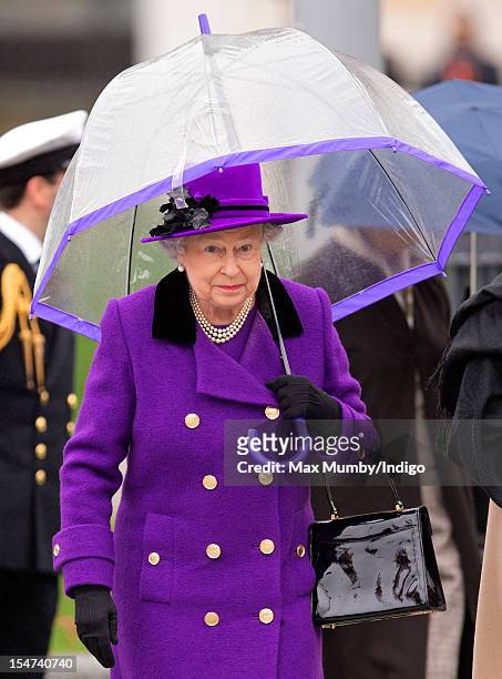 Queen Elizabeth II shelters under an umbrella as attends the opening of the newly developed Jubilee Gardens on October 25, 2012 in London, England.