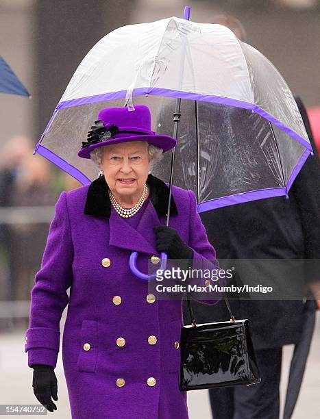 Queen Elizabeth II shelters under an umbrella as attends the opening of the newly developed Jubilee Gardens on October 25, 2012 in London, England.