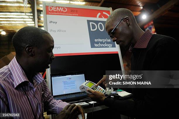 Steve Nyumba listens as entrepreneur Philip Nyamwaya presents an electronic payment system on October 25 during the DEMO Africa technology fair at...