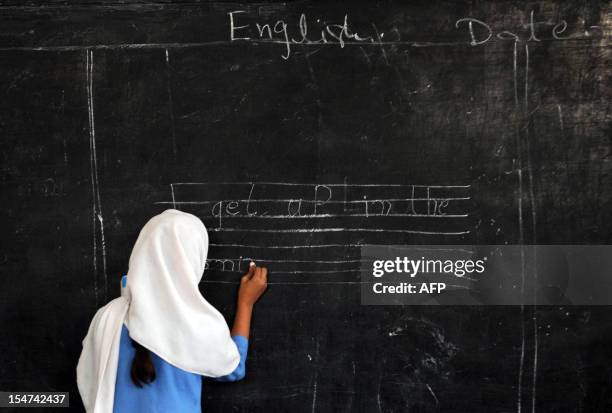 Pakistani female student writes a sentence on a black board at a government school in Peshawar on October 25, 2012. AFP PHOTO/A. MAJEED