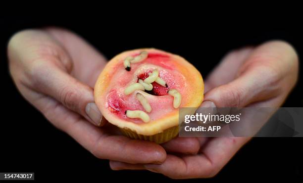 Woman holds a cupcake depicting maggot therapy at the 'Eat Your Heart Out 2012' cake shop in the Pathology Museum in London on October 25, 2012. The...