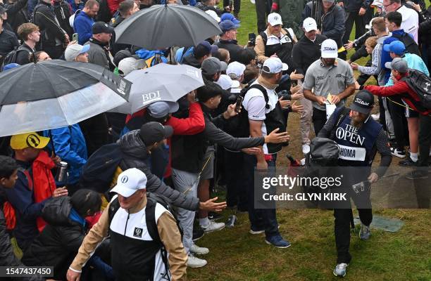 Fans try to touch US golfer Max Homa and Northern Ireland's Rory McIlroy as they walk to the 13th tee on day three of the 151st British Open Golf...