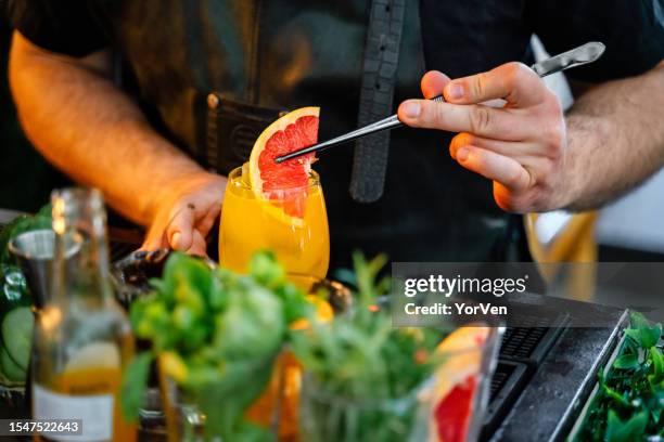 close-up of bartender garnishing a fresh cocktail in the bar - cocktail party work stock pictures, royalty-free photos & images