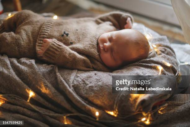snuggly picture of newborn. the baby girl sleeps in a knitted costume, wrapped in a cozy blanket. - snuggly stockfoto's en -beelden