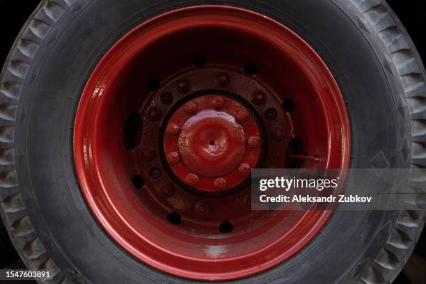 an old red wheel with a black tire of a heavy machine. a part, a working part of a tractor or truck. a wheel of heavy machinery in close-up, in the countryside. non-urban scene. work on the construction site. the concept of agriculture, industry. - non motorised vehicle stock pictures, royalty-free photos & images