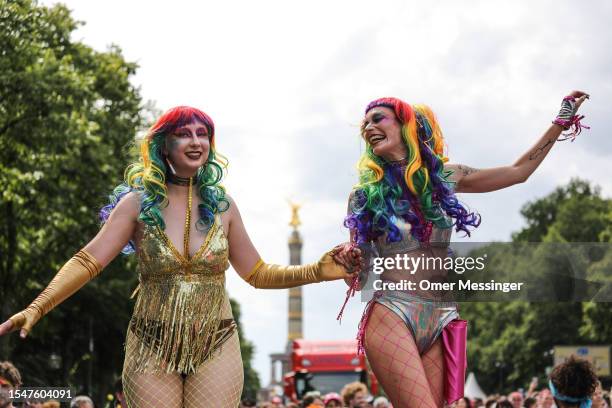 Performers dance next to the drummers group Cortejo-Baiano during the annual Christopher Street Day parade, near the Victory Culumn Siegessäule on...