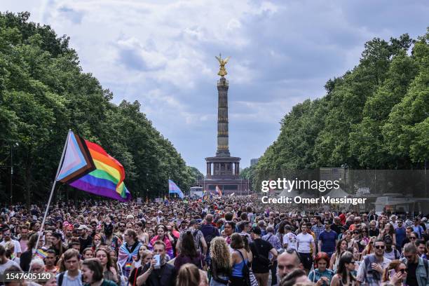 Participant waves the progress pride flag among masses marching during the annual Christopher Street Day parade, near the Victory Culumn Siegessäule...