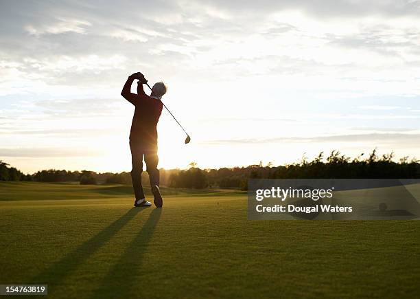 senior golfer teeing off on golf course. - swing de golf fotografías e imágenes de stock