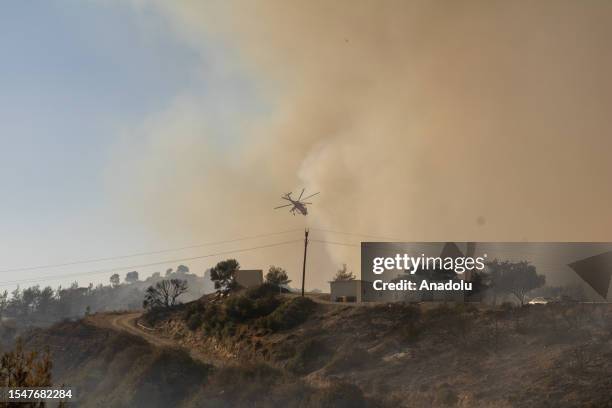 Firefighter helicopter drops water as teams conduct extinguishing works by land and air to control wildfires across Greece's Rhodes island on July...