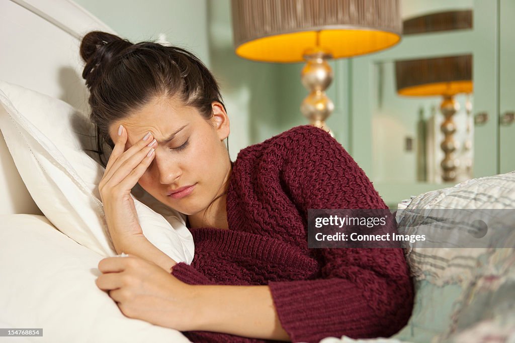 Young woman in bed with headache