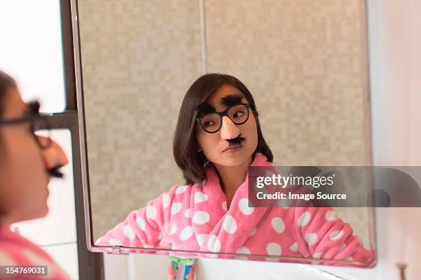 young woman looking herself wearing funny disguise - disguise face stock pictures, royalty-free photos & images