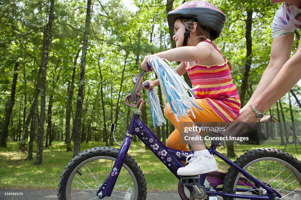 Mother helping daughter to ride bicycle