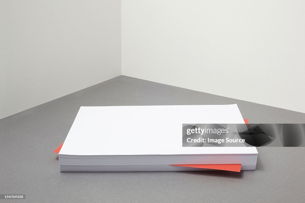 Red piece of paper amongst stack of blank paper