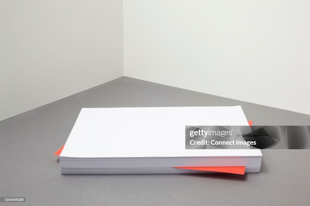 Red piece of paper amongst stack of blank paper