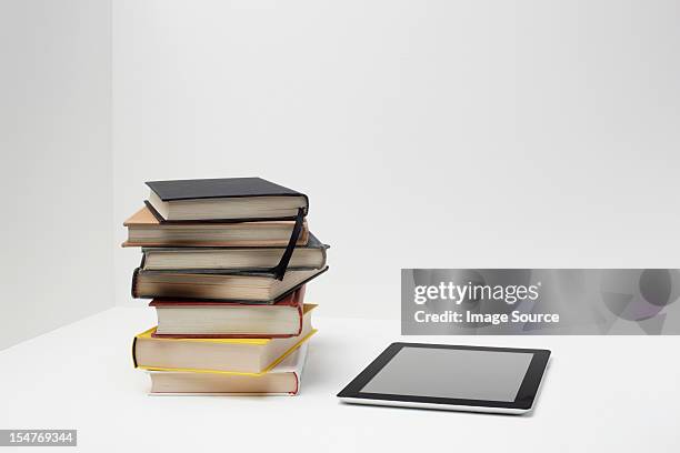 stack of books with digital tablet - pile of books stockfoto's en -beelden