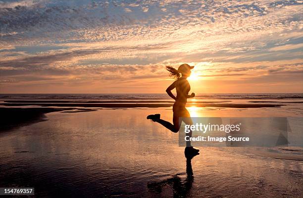 woman running on beach at sunrise - matin photos et images de collection