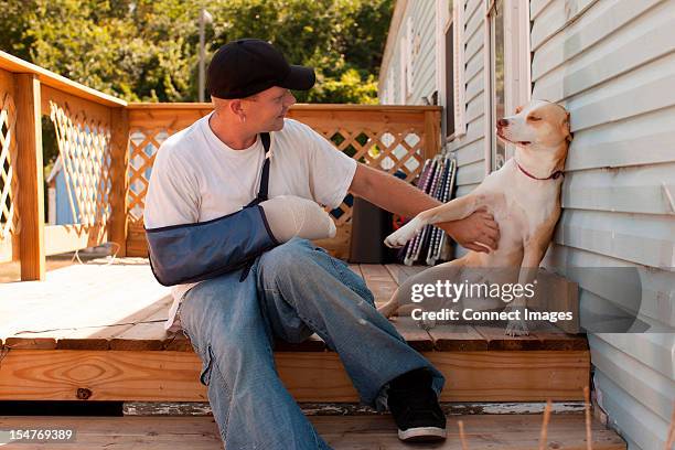 man outside house with arm in sling and dog - broken arm stock pictures, royalty-free photos & images