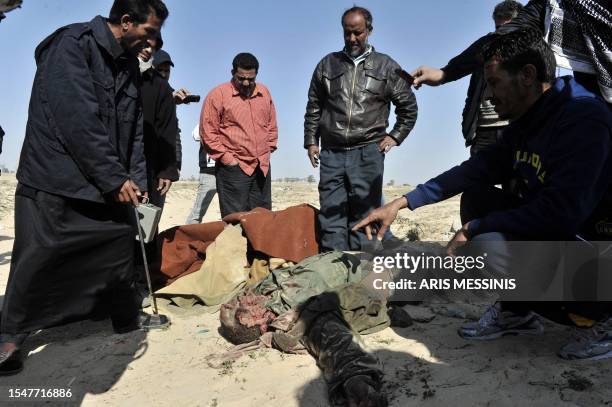 Libyans gather around the body of a dead pro-Kadhafi fighter in the strategic oil town of Ajdabiya whose control was seized by rebels from Colonel...
