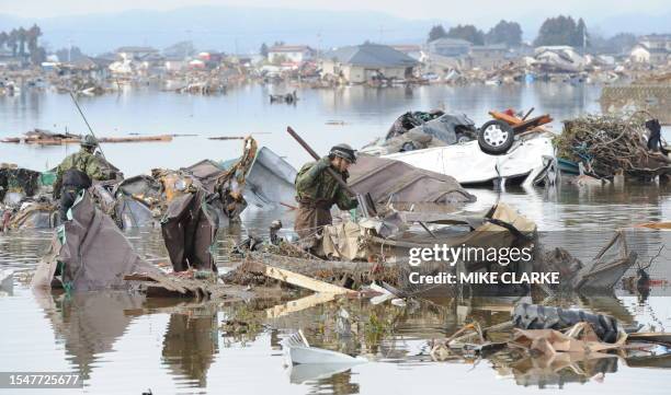 Japanese soldiers search through flooded lowland areas in Natori, Miyagi prefecture on March 16, 2011 after the March 11 earthquake and tsunami. The...