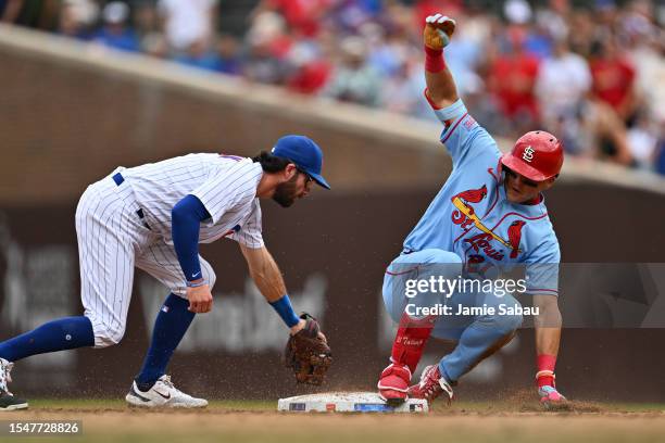 Lars Nootbaar of the St. Louis Cardinals slides in for a double in the third inning ahead of the tag from Dansby Swanson of the Chicago Cubs at...