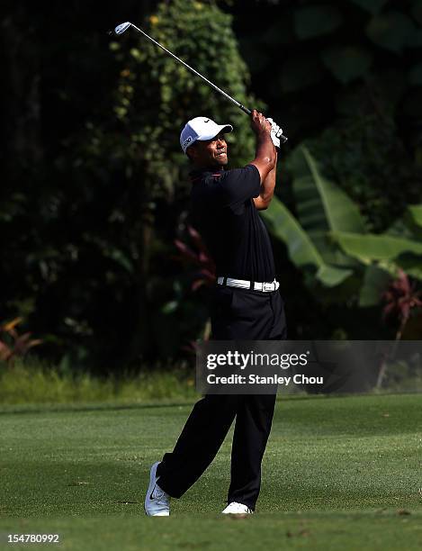 Tiger Woods of USA plays his 2nd shot on the 1st hole while police men looks on during Round One of the 2012 CIMB Classic at the Mines Resort and...