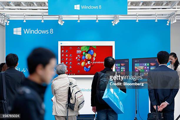 People watch a promotion for Microsoft Corp.'s Windows 8 operating system outside an electronics store in Tokyo, Japan, on Friday, Oct. 26, 2012....