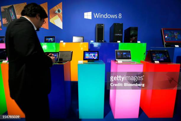 An attendee looks at tablet devices and laptop computers running Microsoft Corp.'s Windows 8 operating system during a launch event in Tokyo, Japan,...