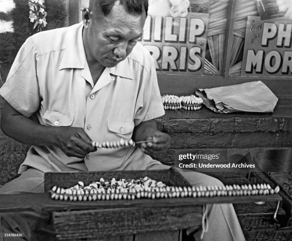 A Hawaiian man stringing puka shell necklaces, Hawaii, circa 1948. News ...