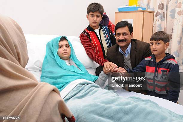 In this handout photo provided by the Queen Elizabeth Hospital Birmingham, Malala Yousafzai sits up in her hospital bed with her father Ziauddin and...