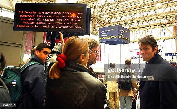 Eurostar passenger gestures towards a sign that reads "All Eurostar and Eurotunnel Services are Suspended. Ferry services are severely disrupted. All...